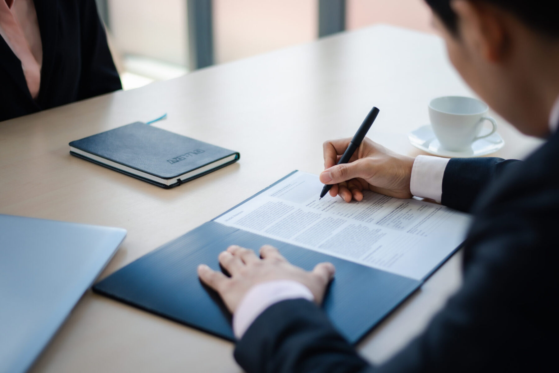 Close up business man writing or signing contract on paper in of Close up business man writing or signing contract on paper in office.